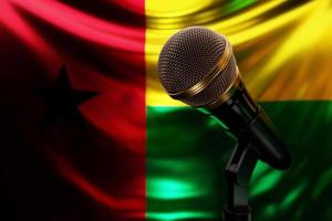 microphone sur le fond du drapeau national de la guinée bissau, illustration 3d réaliste. prix de musique, karaoké, équipement de sonorisation de studio de radio et d'enregistrement photo