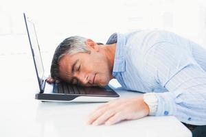 homme aux cheveux gris dormant sur son ordinateur portable