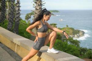 une belle femme en forme de vêtements de sport faisant de l'exercice sur le sommet de la montagne en bord de mer, la santé et le concept de voyage. photo