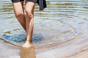 jambe de femme à pied dans une rivière claire et propre avec un lit de sable - les gens se détendent vacances concept de vie lente photo