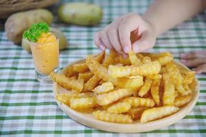 main tenant de délicieuses pommes de terre frites sur une assiette en bois avec sauce trempée - concept traditionnel de restauration rapide photo