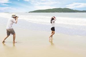 couple sur la plage prenant des photos joyeusement pendant leurs vacances à rayong, thaïlande