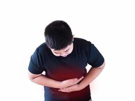 garçon ayant mal au ventre tenant fermement son ventre avec deux mains avec une douleur rouge colorant autour de son estomac photo