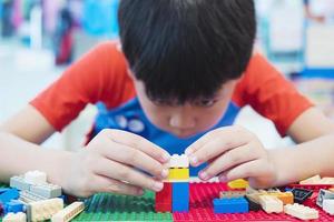 un garçon joue un jeu de puzzle de blocs de jouets colorés pour la pratique du cerveau photo