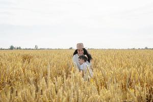 famille heureuse de mère et enfant en bas âge marchant sur le champ de blé photo