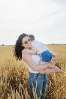 famille heureuse de mère et enfant en bas âge marchant sur le champ de blé photo