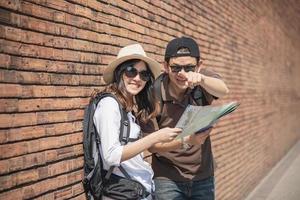 Sac à dos asiatique couple touriste tenant le plan de la ville traversant la route - concept de mode de vie vacances voyage personnes photo