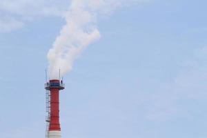 tuyau d'usine avec de la fumée contre le ciel bleu photo