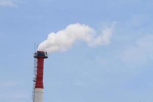 tuyau d'usine avec de la fumée contre le ciel bleu photo