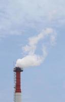 tuyau d'usine avec de la fumée contre le ciel bleu photo