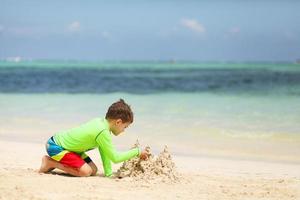 garçon caucasien, construction, château sable, sur, plage tropicale photo