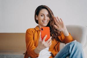 une fille européenne heureuse a un appel vidéo à la maison. écouteurs sans fil utilisés lors d'une conférence en ligne. photo