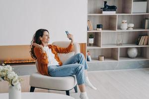 une fille caucasienne heureuse a un appel vidéo à la maison le matin du week-end. la jeune femme utilise des airpods. photo