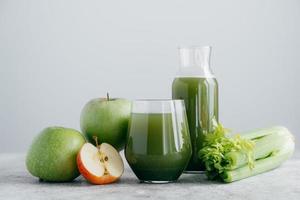 coup horizontal de pommes fraîchement mélangées et cerely pour votre alimentation saine. boisson verte végétarienne dans des verres. boisson détox, fruits et légumes autour photo