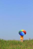 belle femme tenant un parapluie multicolore et un ciel bleu photo