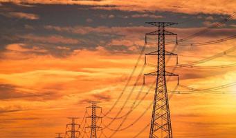 poteau électrique à haute tension et ligne de transmission le soir. pylônes électriques au coucher du soleil. puissance et énergie. tour de réseau haute tension avec câble métallique à la station de distribution avec ciel orange au coucher du soleil. photo