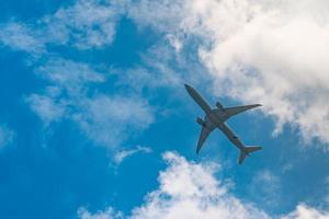 compagnie aérienne commerciale volant sur ciel bleu et nuages blancs moelleux. sous la vue du vol d'avion. avion de passagers après le décollage ou sur le vol d'atterrissage. voyages de vacances à l'étranger. transport aérien. photo