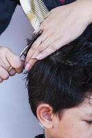 Le coiffeur coupe les cheveux d'un garçon sur fond blanc photo