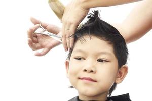 Un garçon est coupé ses cheveux par coiffeur isolé sur fond blanc photo