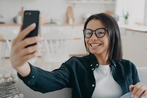 appel téléphonique vidéo. une femme métisse heureuse se détend et discute sur un smartphone. photo