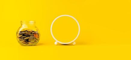 pièce d'argent dans un bocal en verre, concept d'économie d'argent avec espace de copie sur fond jaune. photo