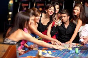 heureux amis caucasiens jouant à la roulette au casino
