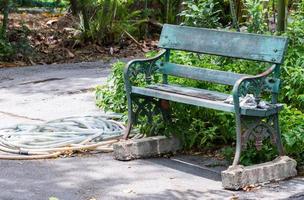 vieux banc en métal avec le tuyau d'arrosage. photo