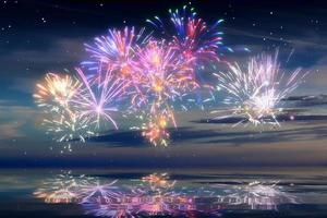 beau feu d'artifice de bonne année dans le ciel avec des reflets sur l'eau photo