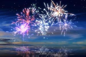 beau feu d'artifice de bonne année dans le ciel avec des reflets sur l'eau photo