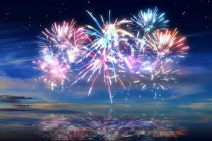 beau feu d'artifice de bonne année dans le ciel avec des reflets sur l'eau photo