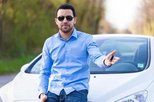 chauffeur latino-américain tenant les clés de voiture au volant de sa nouvelle voiture