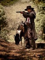 un cow-boy senior debout avec une arme à feu pour protéger la sécurité du camp dans la zone ouest photo