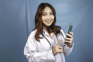 jeune femme médecin asiatique pointe et montre un écran vert ou un espace de copie sur son smartphone photo