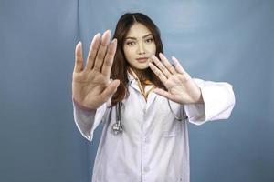 femme médecin asiatique sérieuse avec stéthoscope et blouse blanche, montrant le panneau d'arrêt. photo