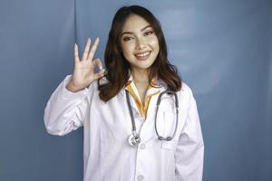 une jeune femme médecin asiatique sourit et montre un signe ok. photo