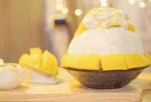 glace à la neige avec garniture à la mangue et à la crème sur une table en bois photo