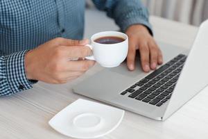 homme travaillant sur un ordinateur portable et boire du café