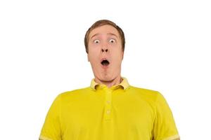 jeune homme surpris avec une drôle de tête avec la bouche grande ouverte en t-shirt jaune isolé sur blanc photo