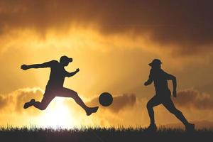 silhouette de joueurs de football dans la soirée. concept de football est populaire partout dans le monde. photo