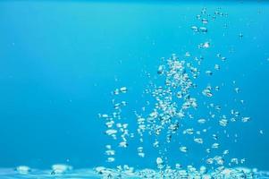 image de fond abstrait de bulles dans l'eau. eau propre avec des gouttelettes d'eau et des vagues. eau douce un verre avec fond bleu bulles. photo