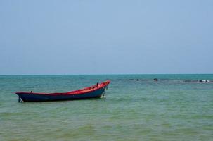 vue paysage petit bateau de pêche en bois vieux garé côte la mer. après la pêche des pêcheurs dans petit village c'est la petite pêcherie locale. ciel bleu, nuages blancs, temps clair, plage de phala, rayong photo