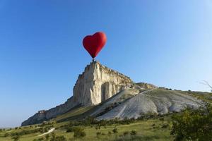 ballon à air chaud, ballon rouge en forme de coeur volant sur fond de roche blanche. photo