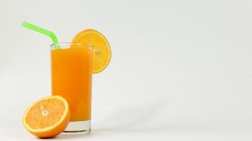 Un verre de jus d'orange avec orange coupé en deux isolé sur fond blanc avec tuyau vert photo