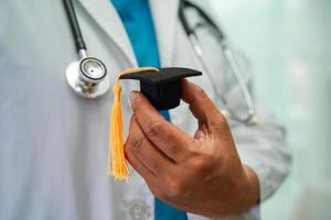 femme médecin asiatique tenant un chapeau de graduation à l'hôpital, concept d'éducation médicale. photo