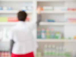 pharmacien flou prenant des médicaments sur une étagère en pharmacie photo