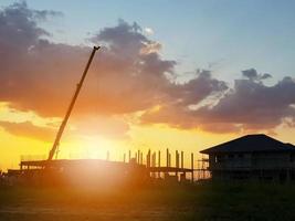 bâtiment de maison de silhouette au fond de coucher de soleil de chantier de construction photo