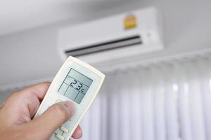 main à l'aide de la télécommande avec climatiseur dans la chambre photo