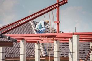 ouvriers soudeurs installant une structure à ossature en acier du toit de la maison sur le chantier de construction photo