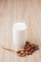 lait d'amande en verre avec des noix autour sur fond de bois.mise au point sélective.vue de face.espace de copie. photo