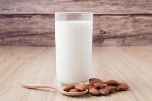 lait d'amande en verre sur fond de bois avec des noix autour du bol. photo